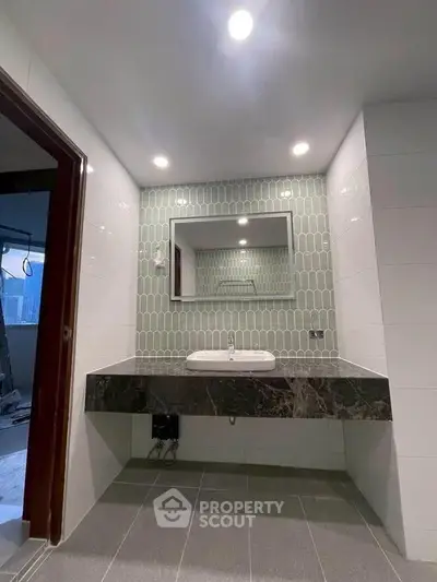 Modern bathroom with stylish tile backsplash and sleek vanity in a contemporary apartment.