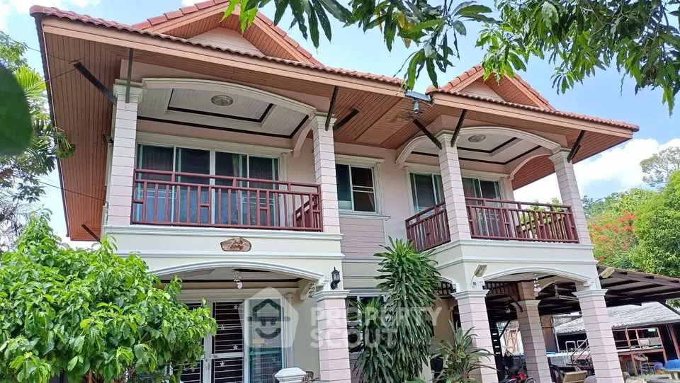 Charming two-story house with twin balconies and lush greenery