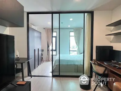 Modern studio apartment with glass partition, stylish workspace, and cozy bedroom area.