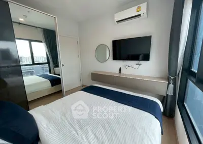 Modern bedroom with large windows and wall-mounted TV in a stylish apartment.