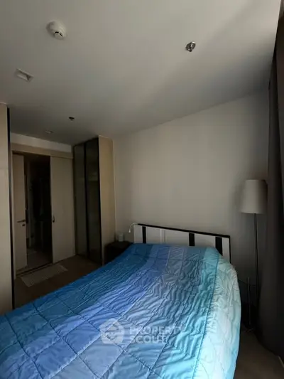 Modern bedroom with cozy blue bedding and sleek wardrobe in a stylish apartment.