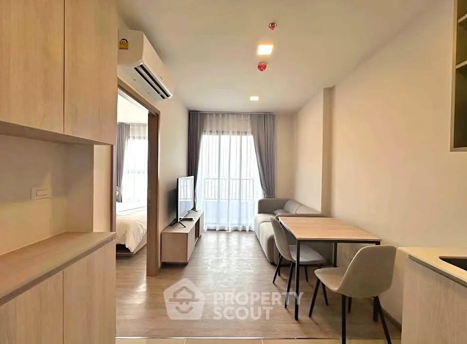 Modern living room with dining area and bedroom view in open-plan apartment