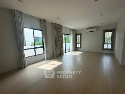 Spacious sunlit living room with large windows and modern flooring