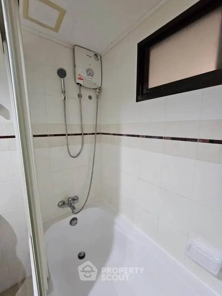 Compact bathroom with bathtub and water heater, ideal for small apartments.