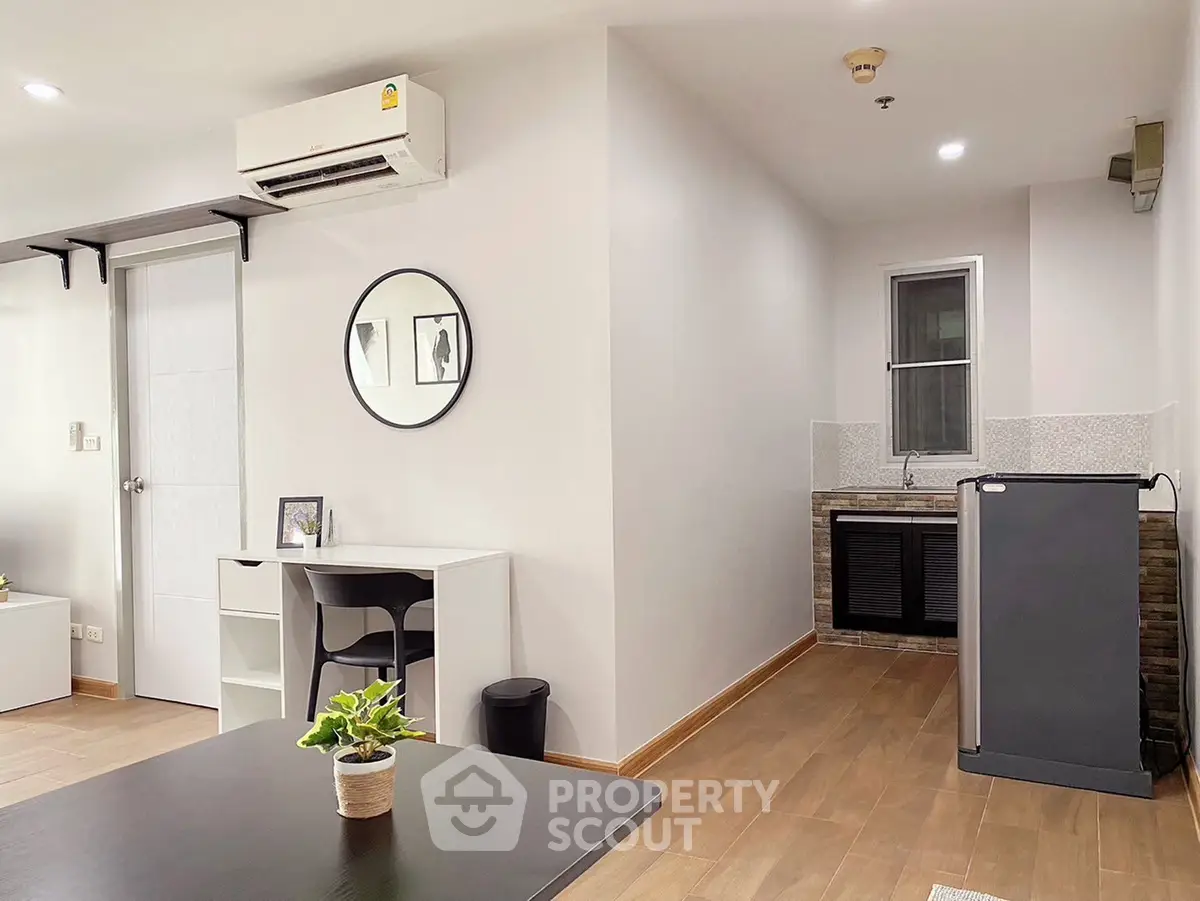 Modern studio apartment with sleek design, featuring a compact kitchen and stylish workspace.
