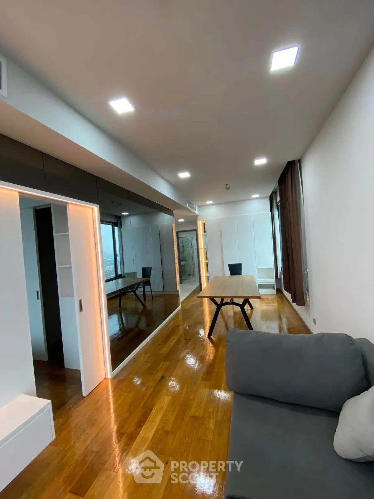 Modern living room with sleek design, wooden flooring, and large windows offering natural light.
