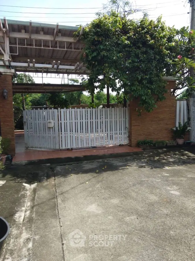 Charming gated entrance with lush greenery and spacious driveway