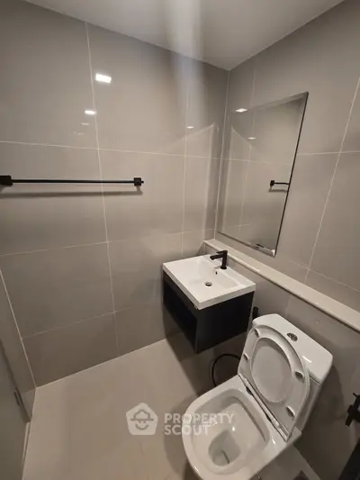 Modern bathroom with sleek fixtures and minimalist design, featuring a wall-mounted sink and toilet.