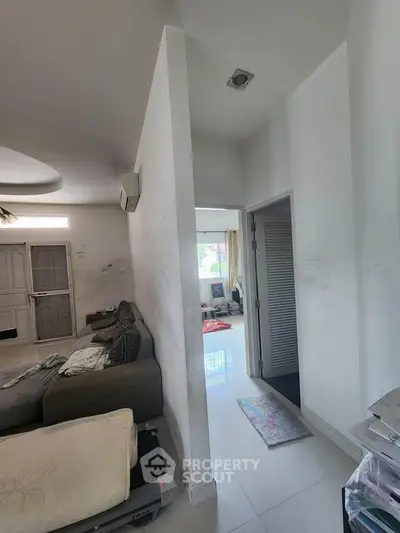 Spacious living area with modern decor and ample natural light, featuring a cozy sofa and sleek flooring.