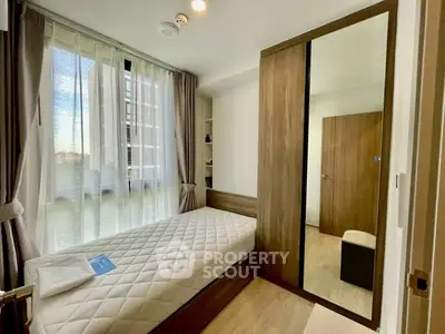 Modern bedroom with large window and mirrored wardrobe in stylish apartment.