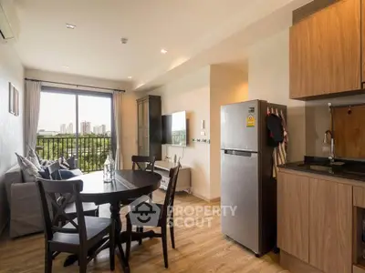 Modern open-plan living room with kitchen, featuring wooden flooring and a scenic balcony view.