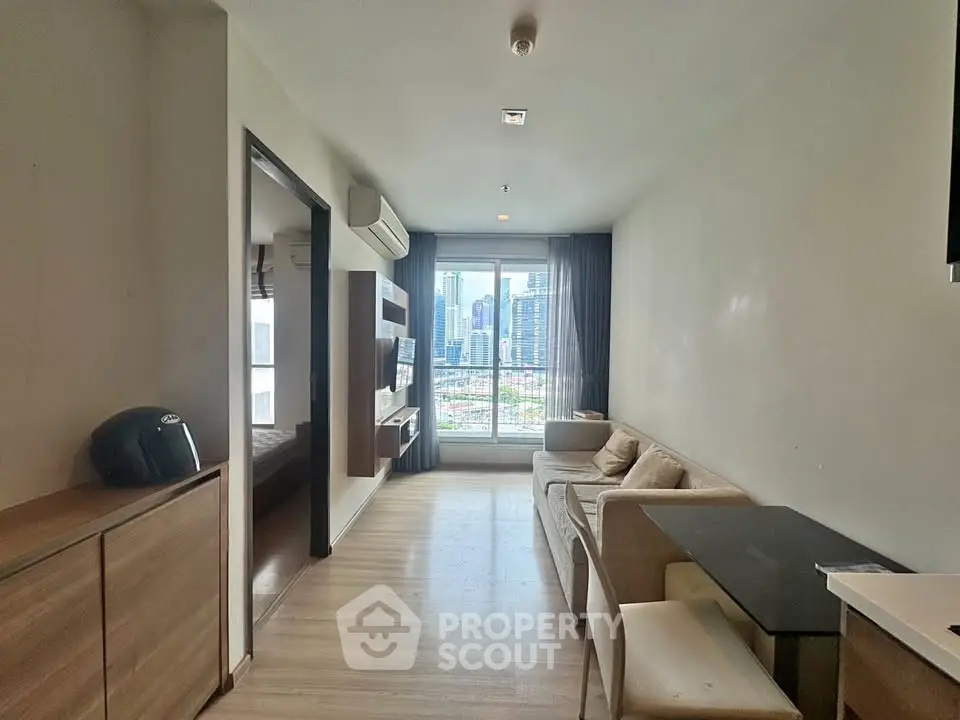 Modern living room with city view, featuring sleek furniture and large window for natural light.