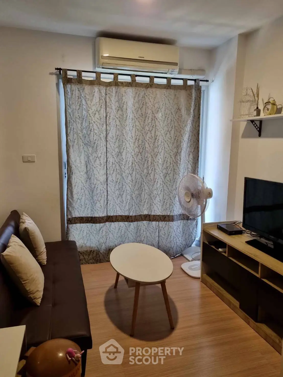 Cozy living room with modern decor and air conditioning, featuring a stylish sofa and entertainment unit.