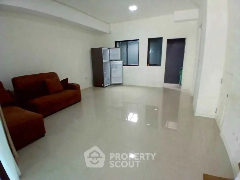 Spacious living room with modern furniture and large refrigerator, perfect for comfortable living.