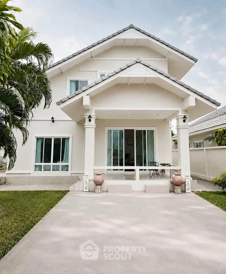 Charming two-story white house with lush greenery and spacious driveway