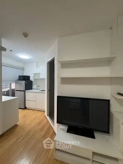 Modern compact living room with integrated kitchen and sleek wooden flooring.