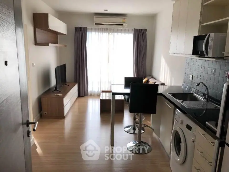 Modern open-plan living room with kitchen, featuring natural light and stylish furnishings.