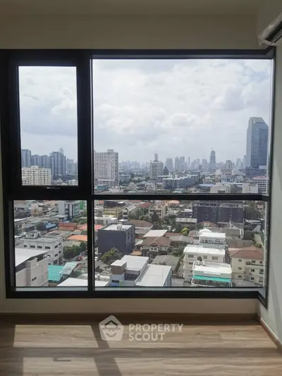 Spacious high-rise apartment with floor-to-ceiling windows offering a panoramic cityscape view, blending urban living with a touch of nature.