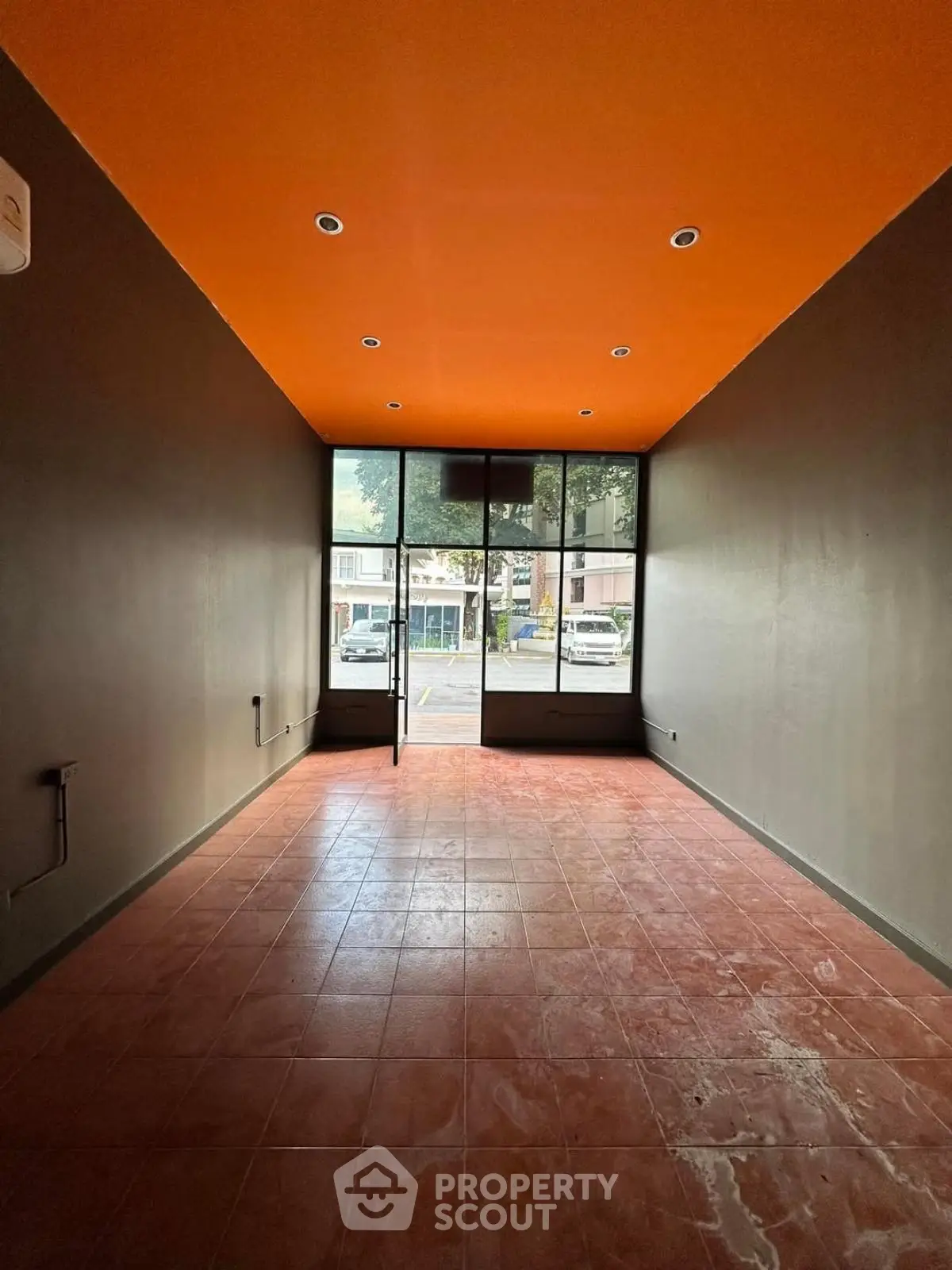 Spacious commercial space with vibrant orange ceiling and large front windows