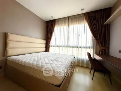 Spacious bedroom with large window and elegant furnishings in modern apartment.