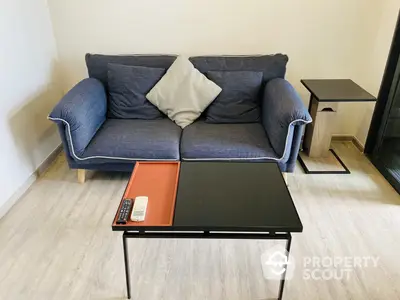 Cozy living room setup with a stylish blue fabric sofa, modern black coffee table, and sleek side table, perfect for urban living.