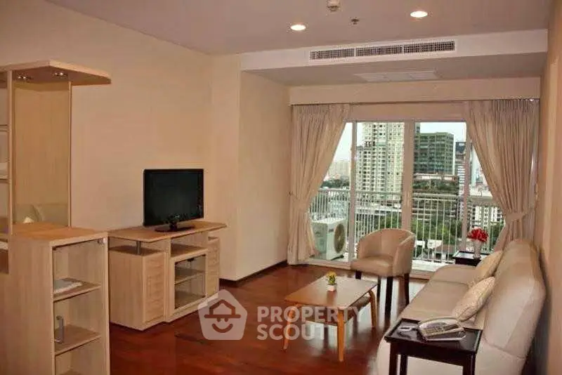 Spacious living room with modern furniture and city view balcony in a high-rise apartment.