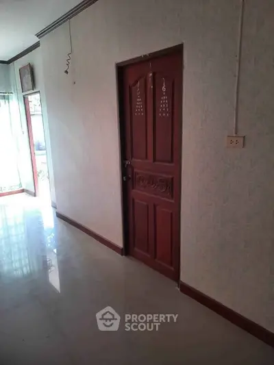 Spacious hallway with elegant wooden door and natural light from large window.