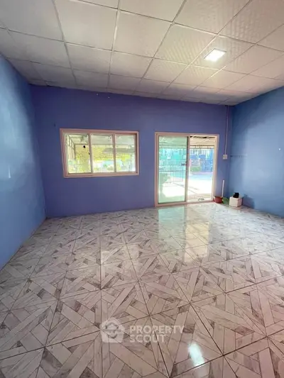 Spacious empty room with tiled floor and large windows offering natural light