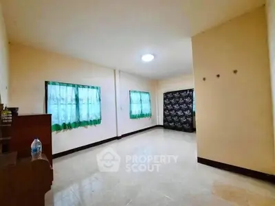 Spacious empty room with tiled flooring and natural light from windows.