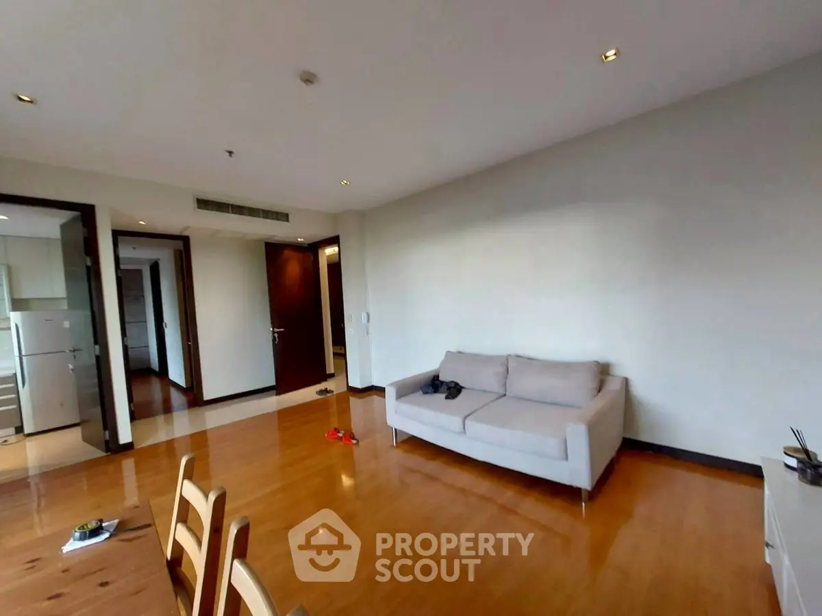 Spacious living room with wooden flooring and modern furniture in a stylish apartment.