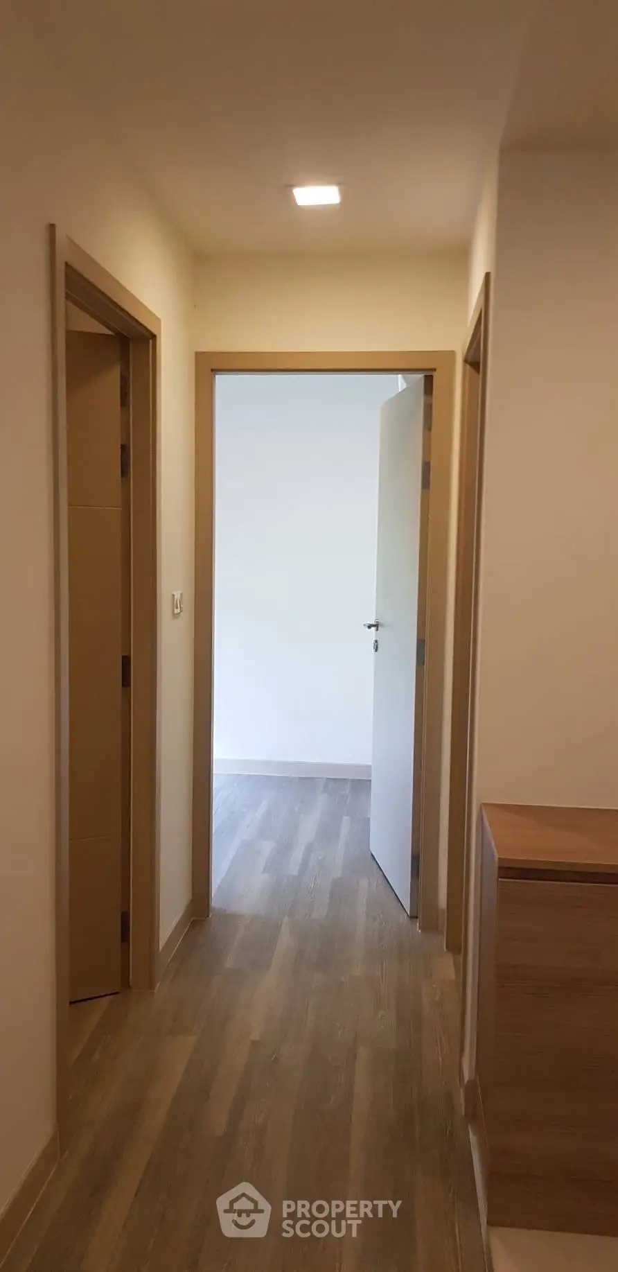 Modern apartment hallway with wooden flooring and open door