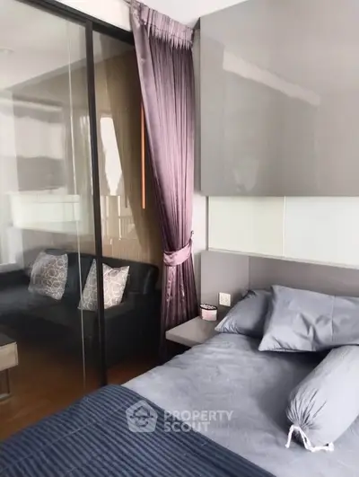 Modern bedroom with sleek design and glass partition leading to cozy living area.