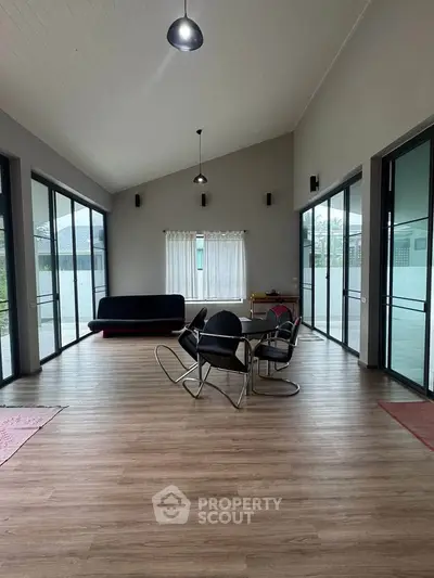 Spacious modern living room with high ceilings and large windows, featuring stylish furniture and abundant natural light.