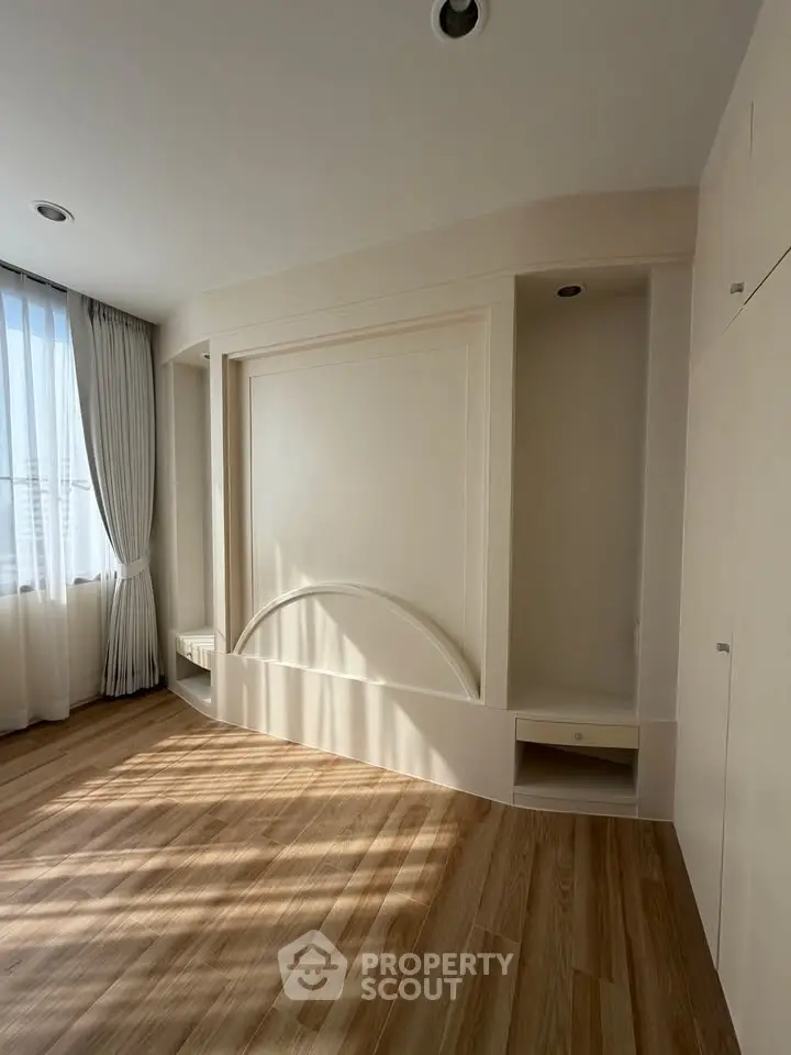 Spacious empty room with elegant wood flooring and natural light, perfect for customization.