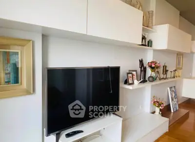 Modern living room with sleek TV and stylish decor on white shelves.