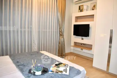 Modern bedroom with stylish decor and wall-mounted TV in a cozy apartment.