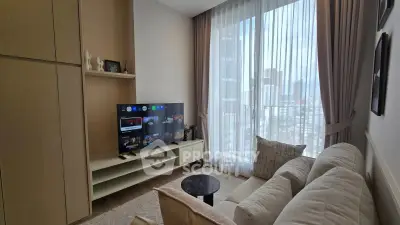 Modern living room with cozy sofa, large TV, and city view through floor-to-ceiling windows.