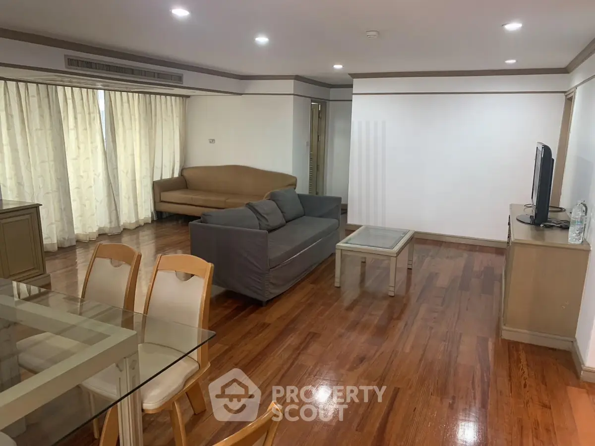 Spacious living room with wooden flooring and modern furniture in a stylish apartment.