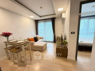 Modern living room with cozy sofa and dining area, featuring large windows and elegant decor.