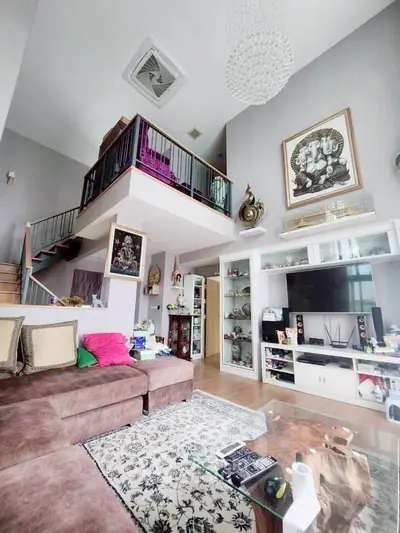 Spacious living room with high ceiling and mezzanine, featuring modern decor and entertainment setup.