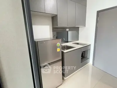 Modern compact kitchen with sleek cabinetry and stainless steel appliances in a stylish apartment.