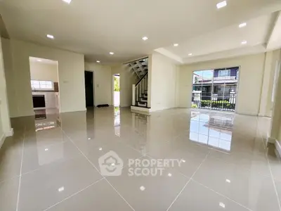 Spacious open-plan living room with glossy tiled floors and modern staircase