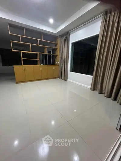 Spacious room with modern shelving and large window, perfect for versatile living space.