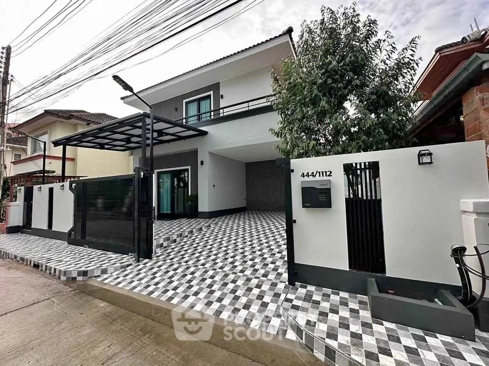 Modern two-story house with stylish checkered driveway and sleek exterior design.