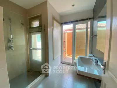 Spacious bathroom with modern shower and dual sinks, featuring large windows for natural light.