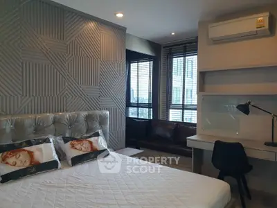 Modern bedroom with stylish decor and natural light, featuring a cozy workspace and air conditioning.