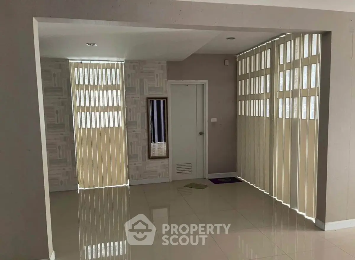 Spacious interior with modern vertical blinds and glossy tiled flooring, ideal for versatile living space.