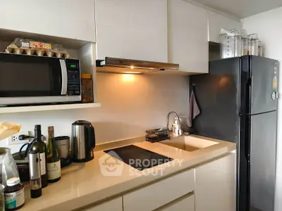 Modern kitchen with sleek cabinetry, black fridge, and built-in microwave, ideal for urban living.