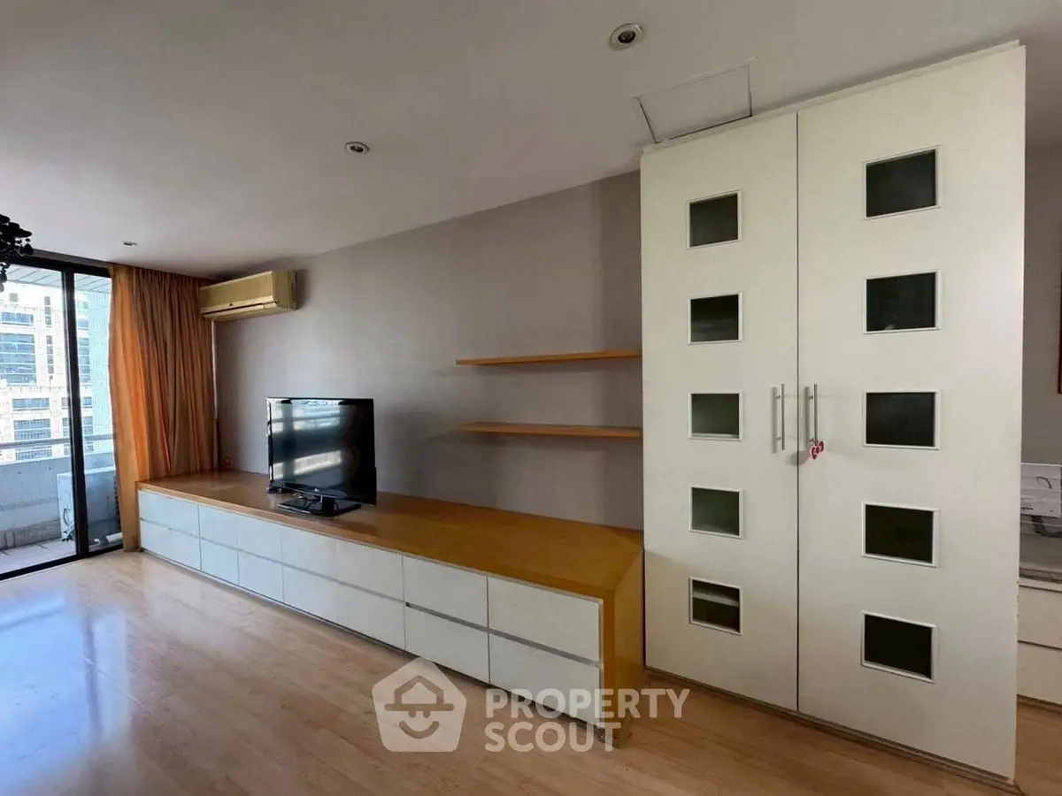 Spacious living room with modern entertainment unit and balcony view.