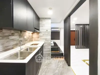 Modern kitchen with sleek cabinetry and open layout leading to living area